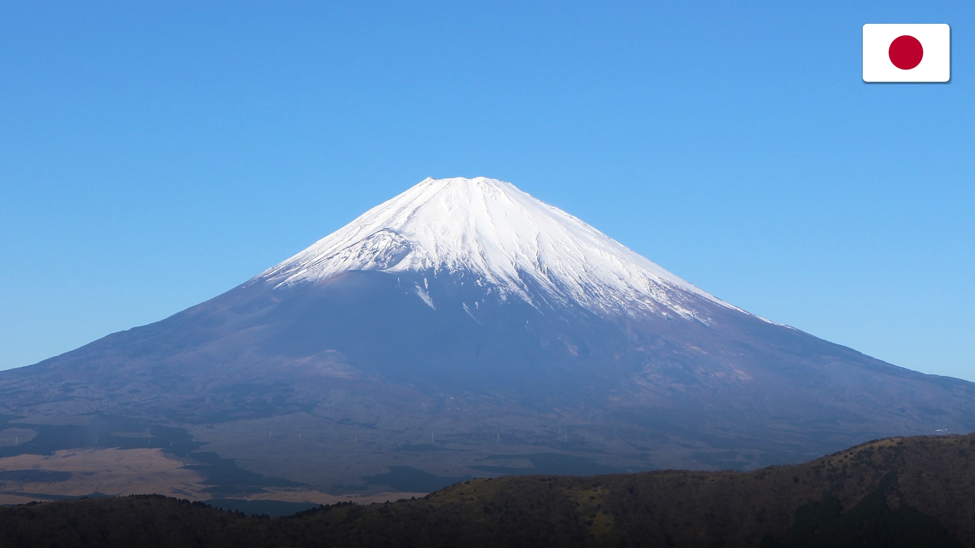 Red Chureito Pagoda framing the snow-capped peak of Mount Fuji during spring.