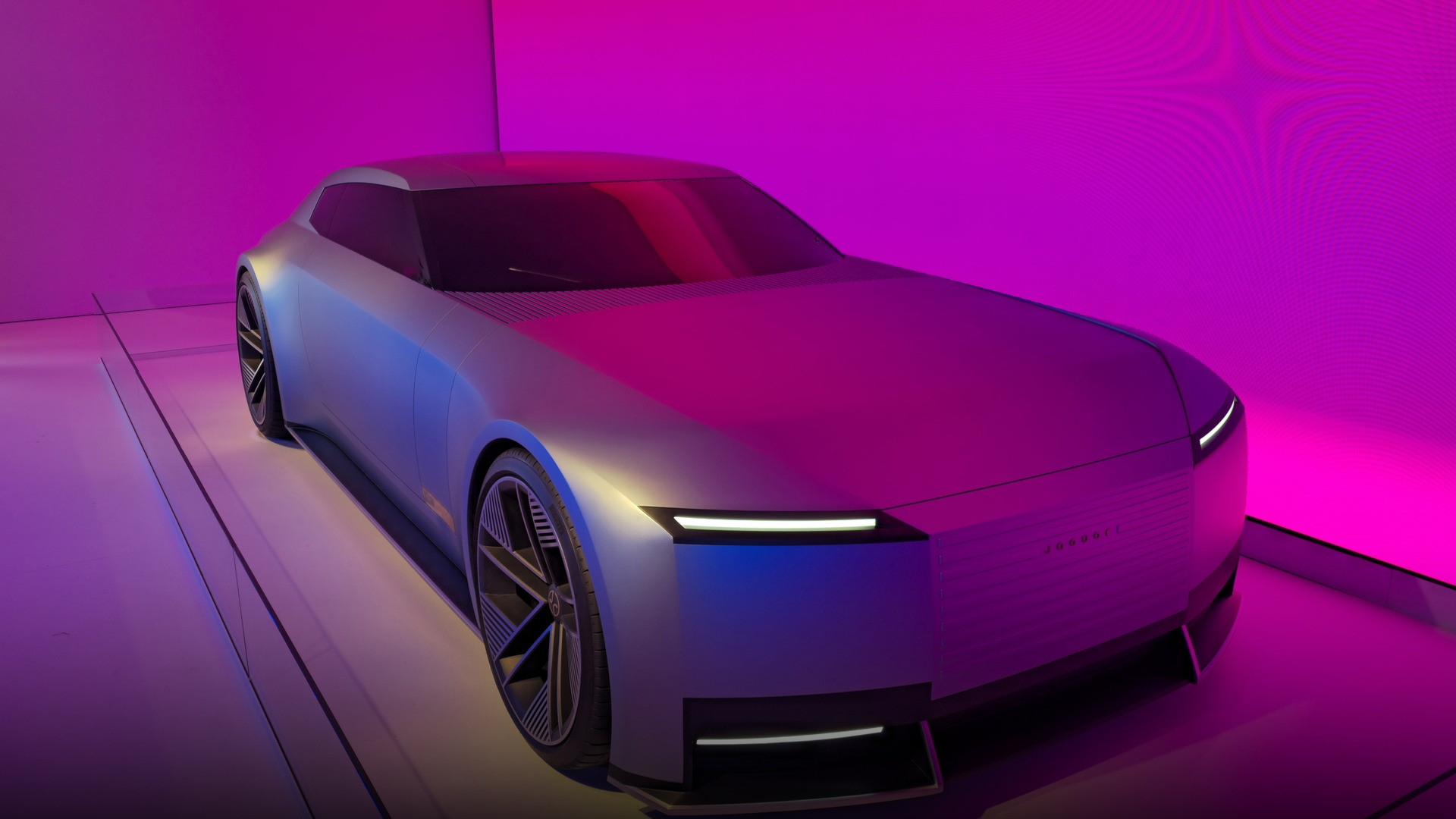 Atmospheric showroom lighting accentuating the wide stance and aggressive performance lines of the Jaguar Type 00.