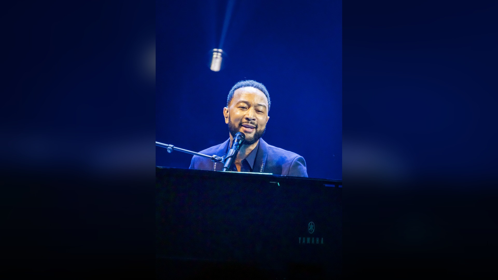 High-resolution portrait photograph of John Legend celebrating academic achievement.