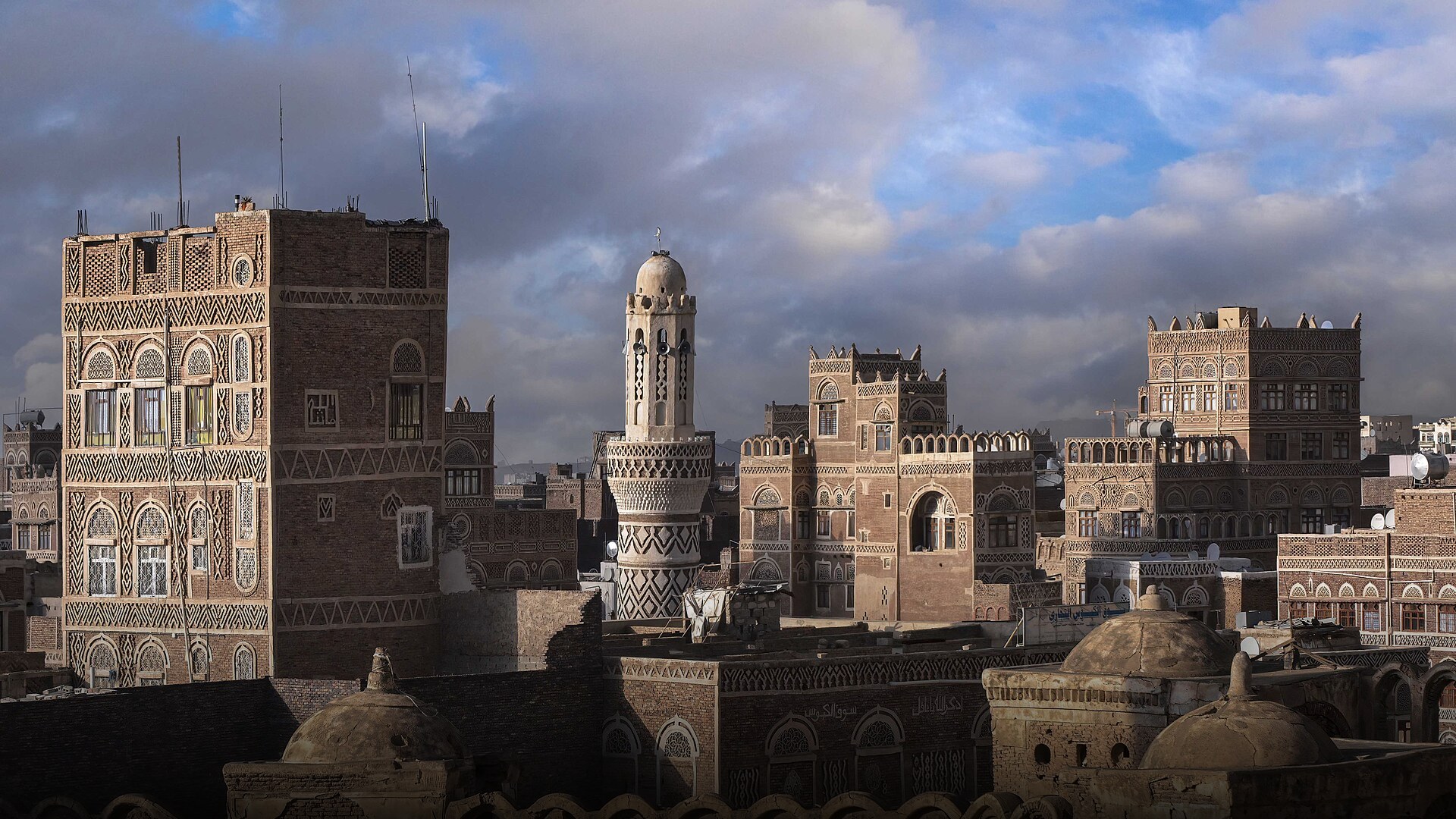 Intricate multi-story clay tower houses with white gypsum filigree decorations in the historic Old City of Sana'a, Yemen.