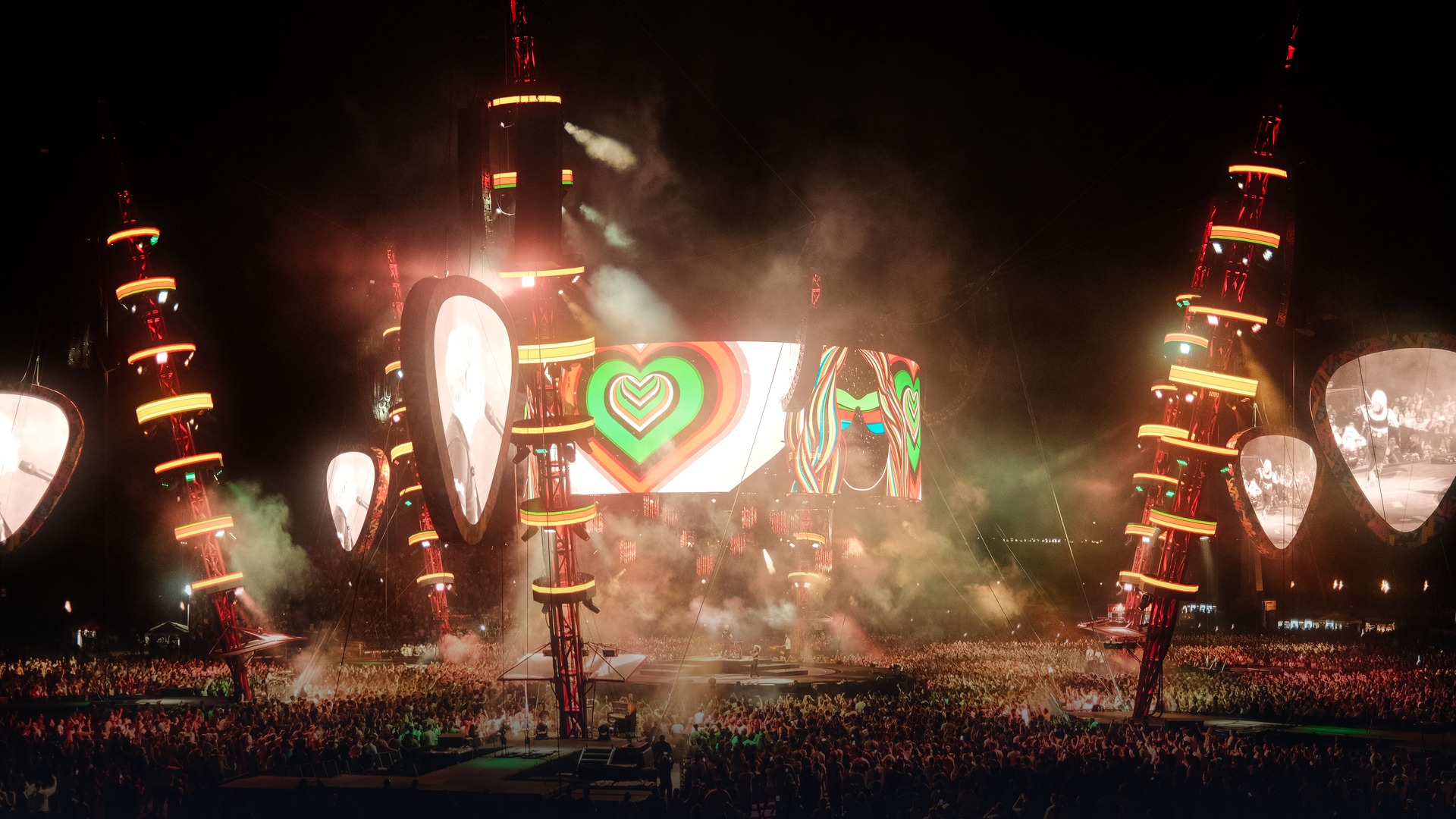 Ed Sheeran performing live in front of tens of thousands of fans under vibrant concert lights.