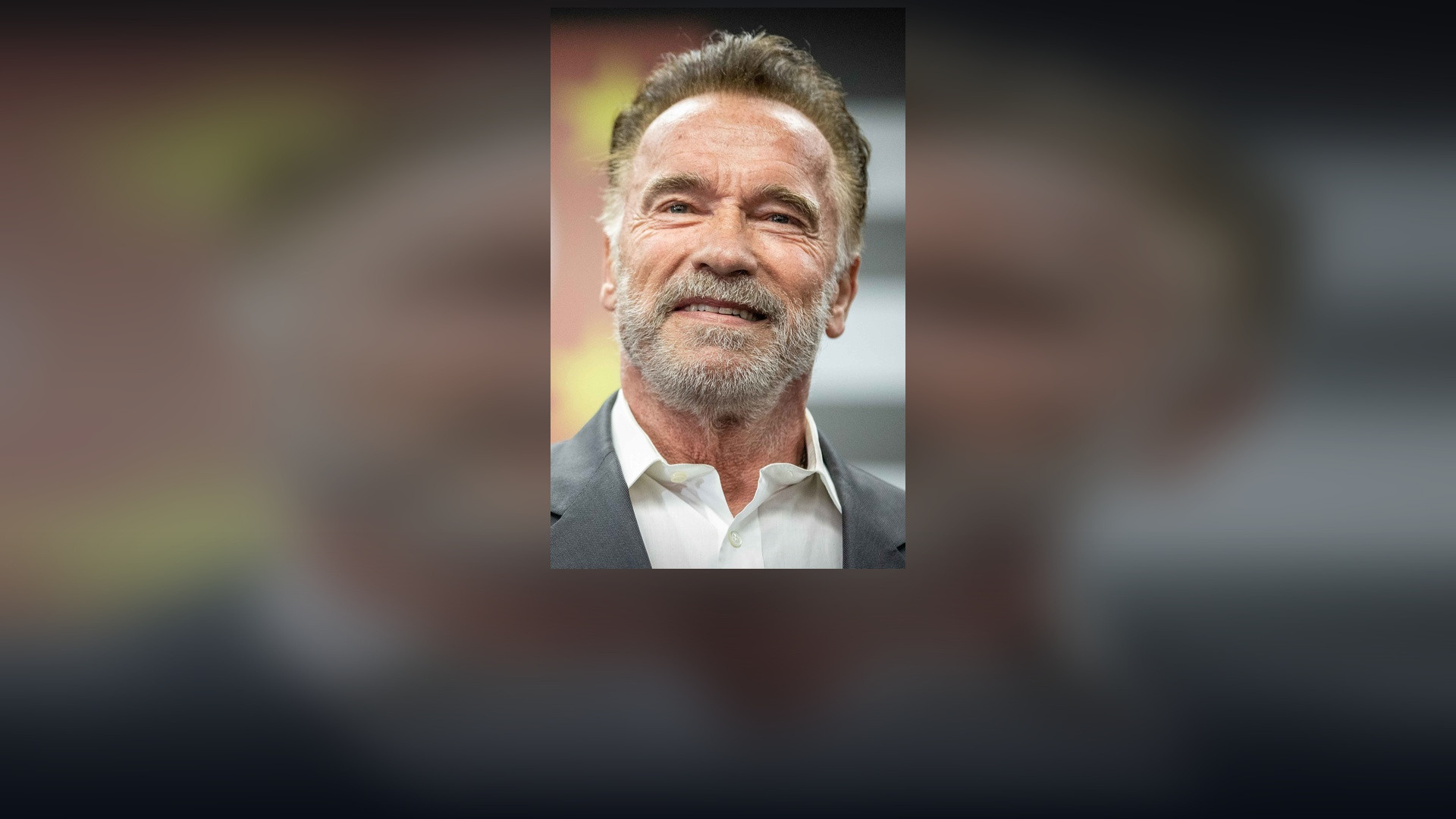 Arnold Schwarzenegger speaking on stage at a convention in 2019.