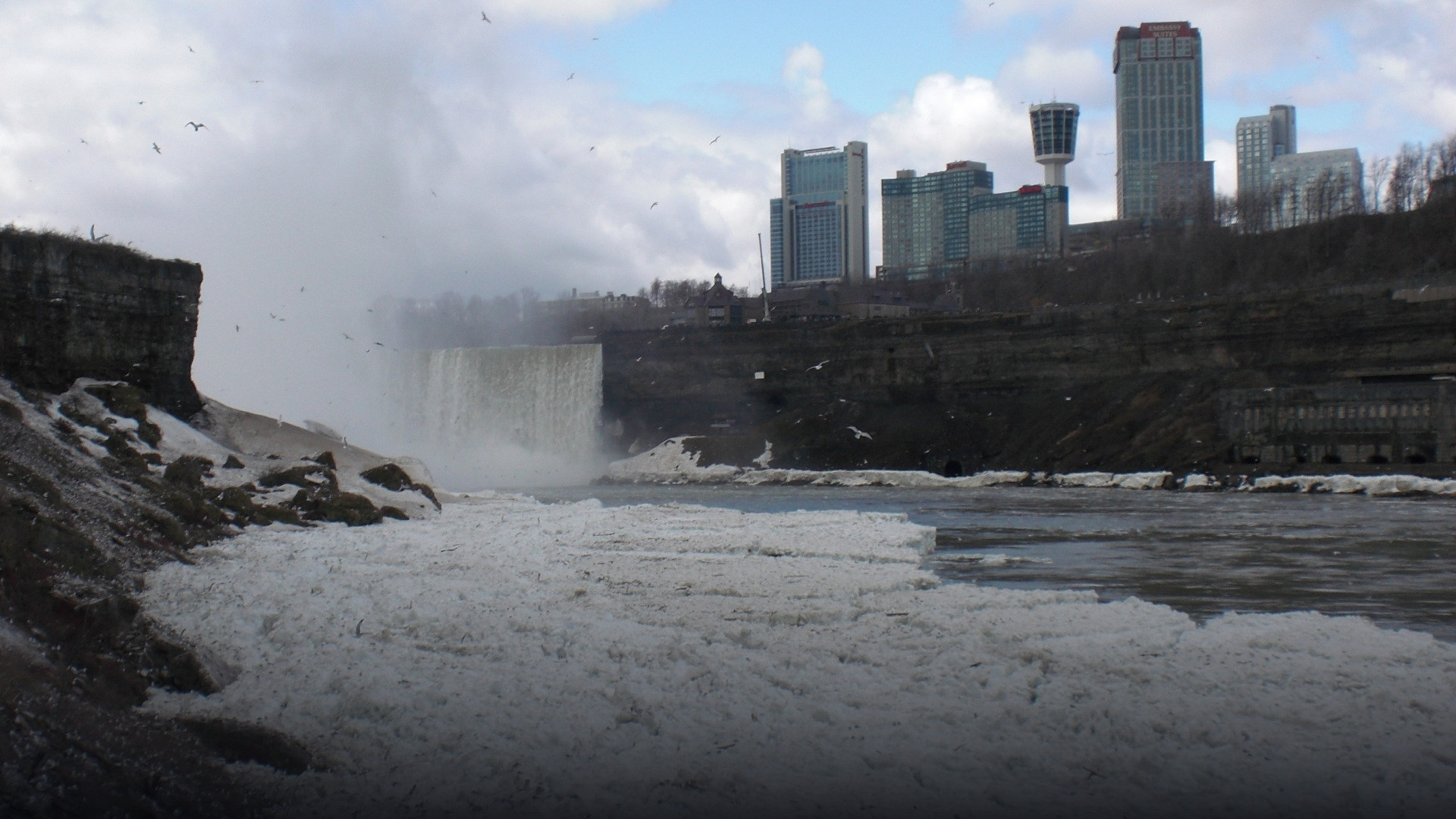 The frozen mist and massive snow drifts encasing the roaring Niagara Falls in winter.