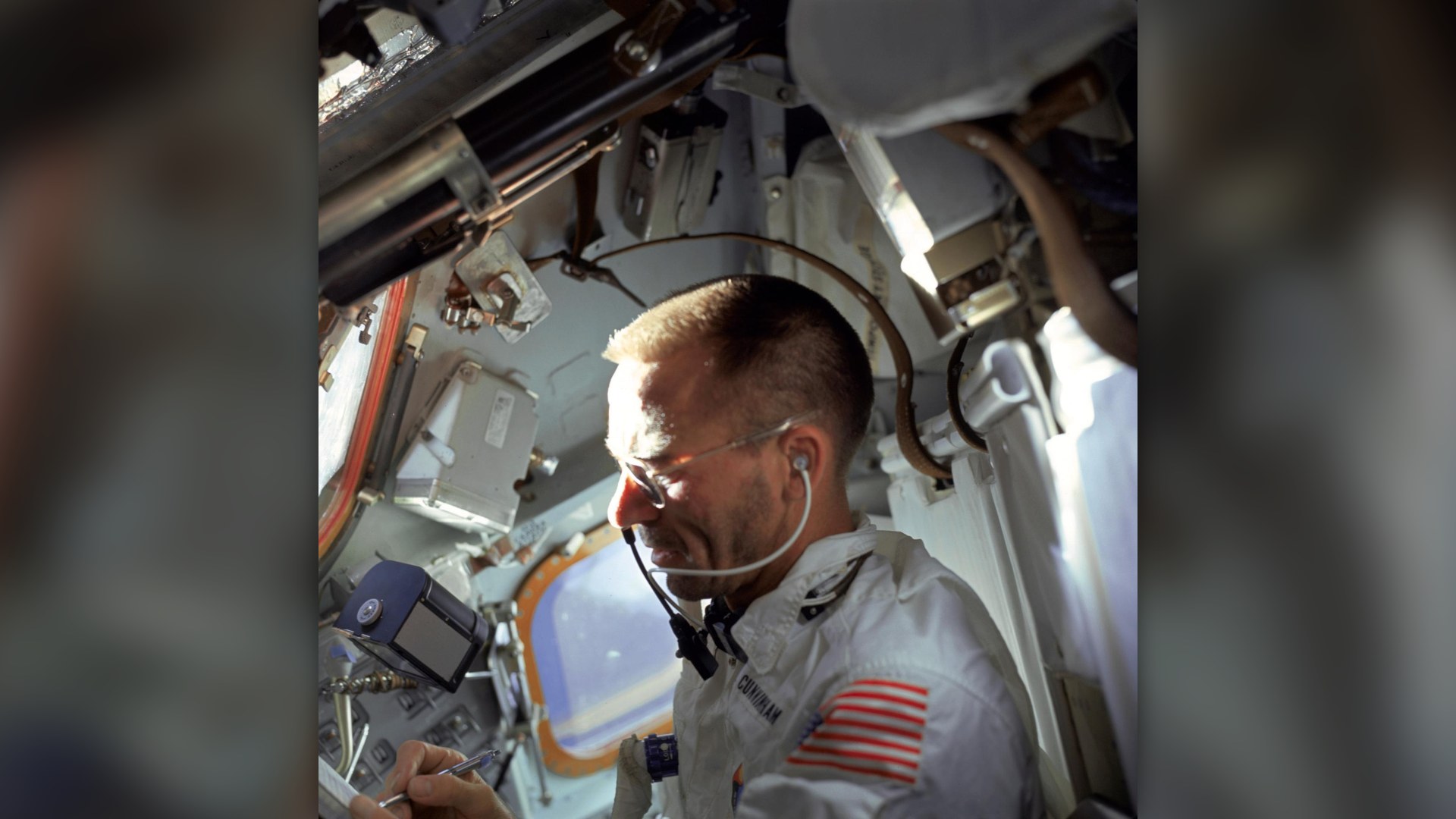 Apollo 7 astronaut Walter Cunningham writing aboard the spacecraft