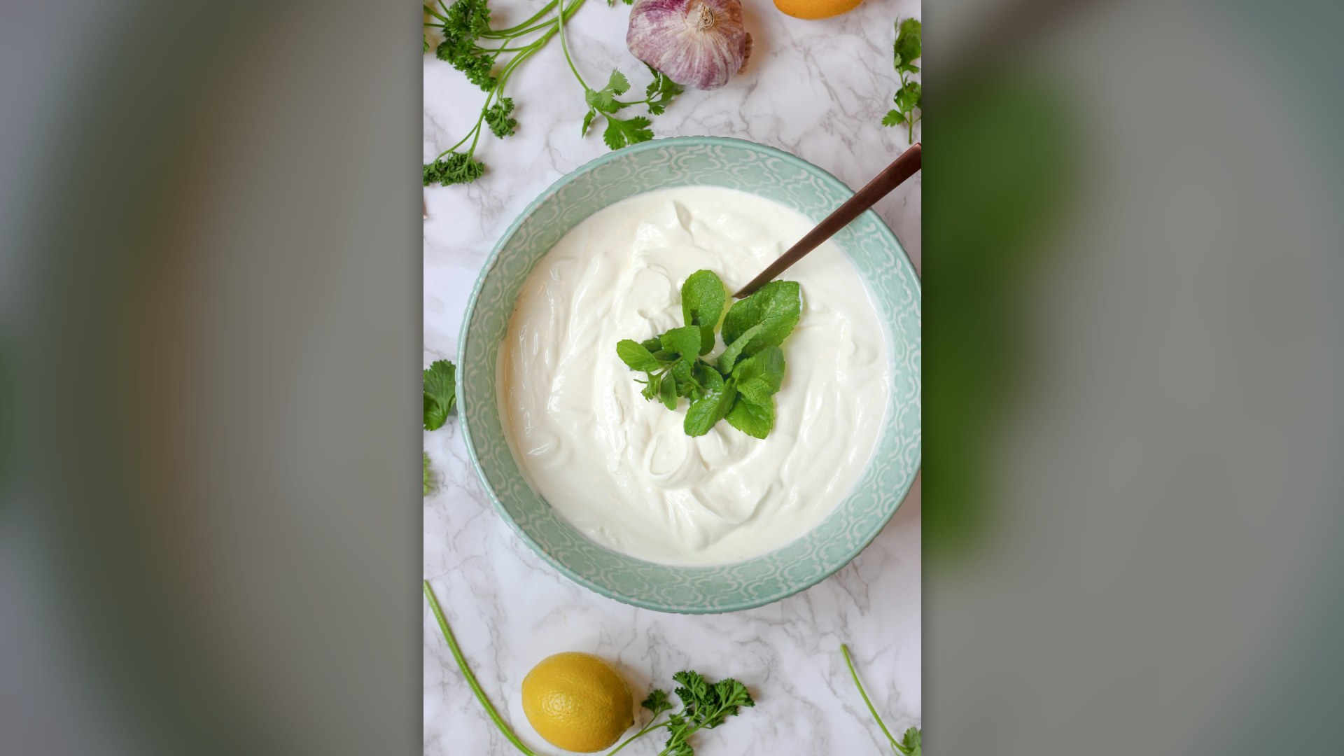 Plain creamy Greek yogurt in a teal decorative bowl on marble