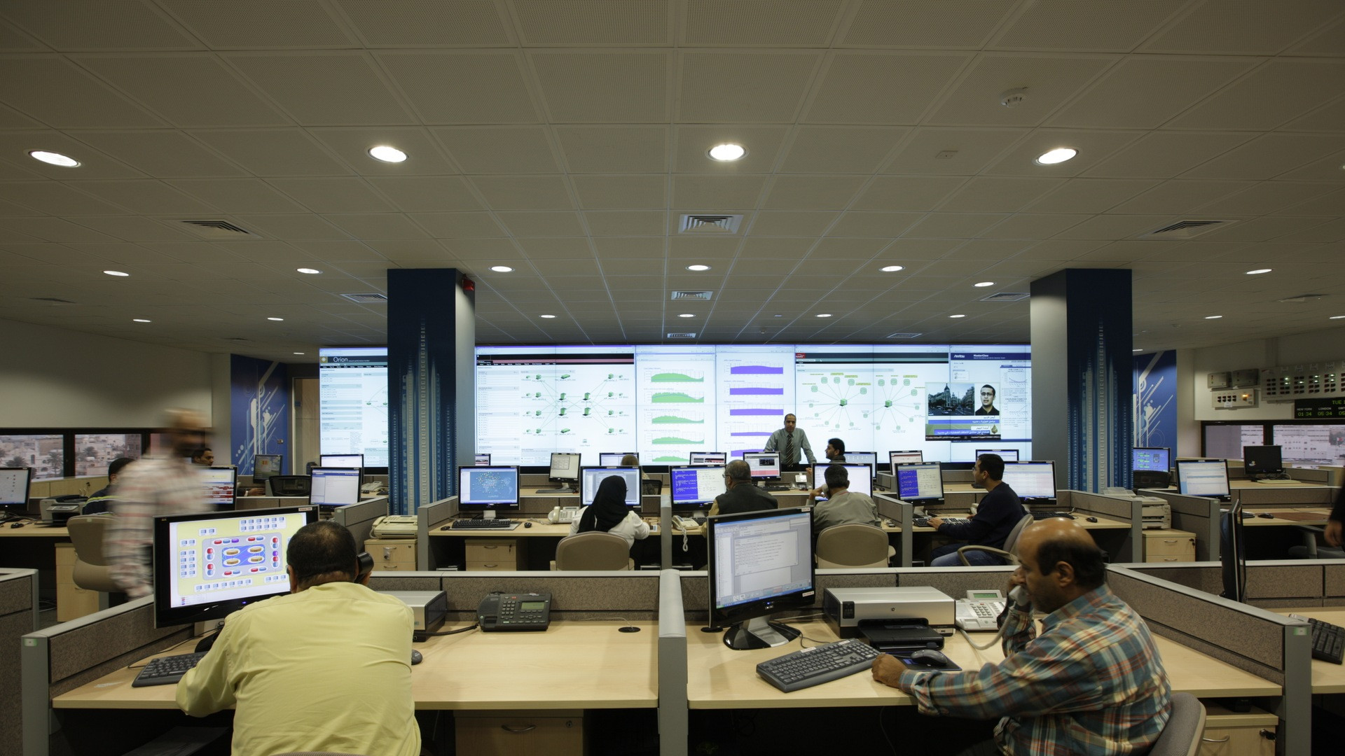 Vast mission control and network operations center with dozens of wall-sized monitoring screens.