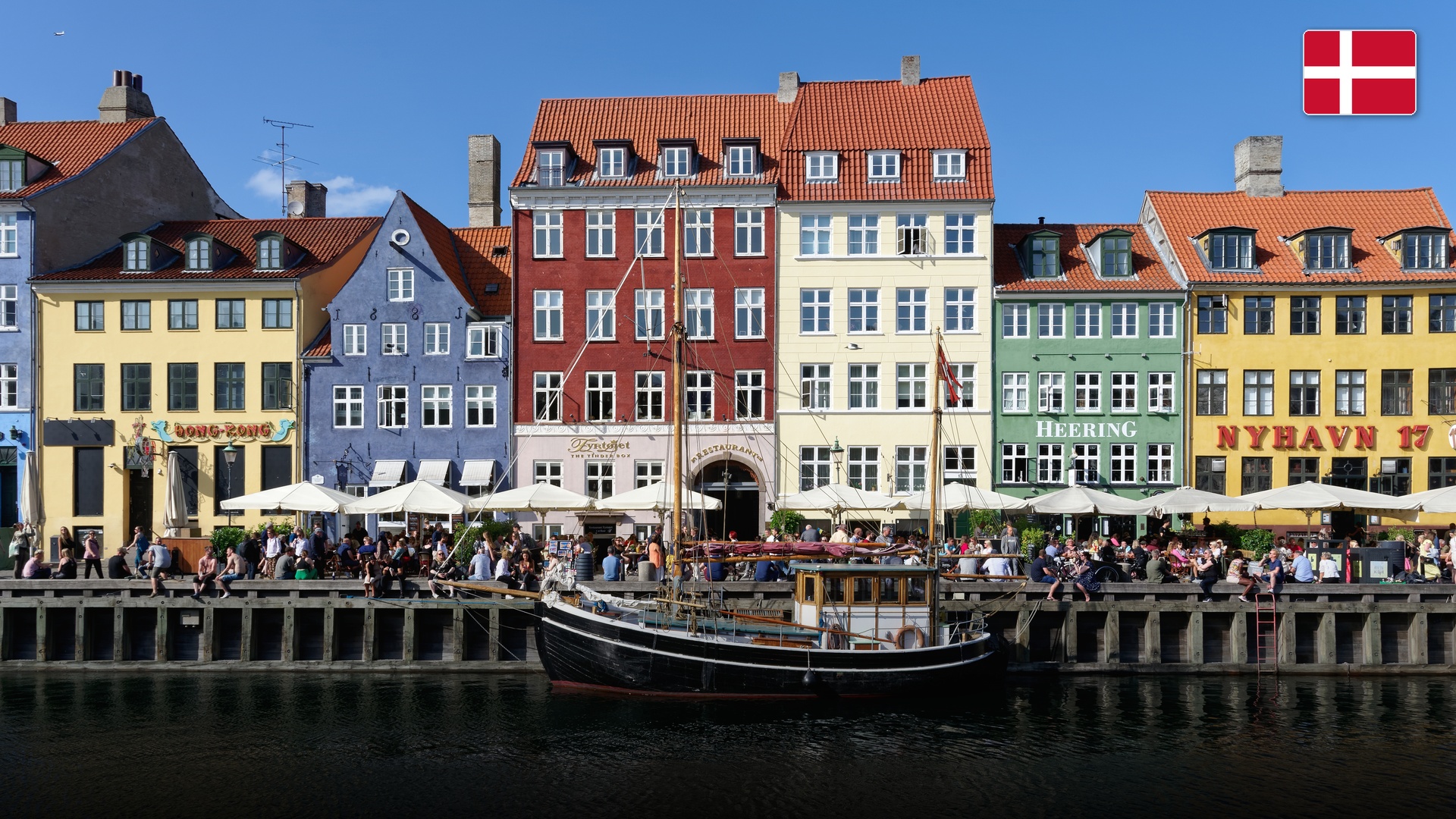 Nyhavn harbor canal in Copenhagen lined with colorful 17th-century townhouses and wooden ships.