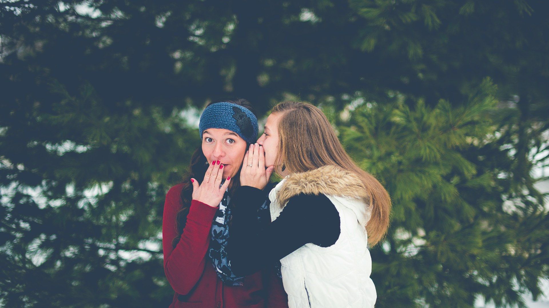 Woman whispering a secret into another woman's ear