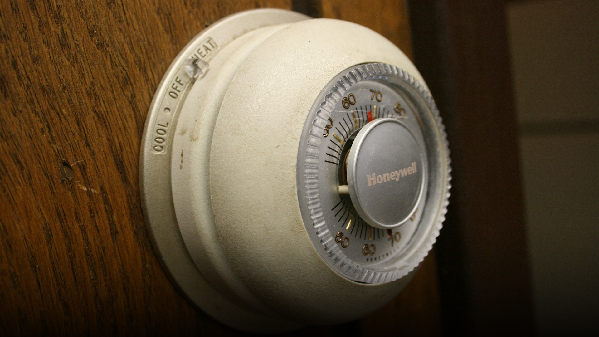 Iconic round Honeywell T87 thermostat dial mounted on a wall displaying temperature settings in Fahrenheit.