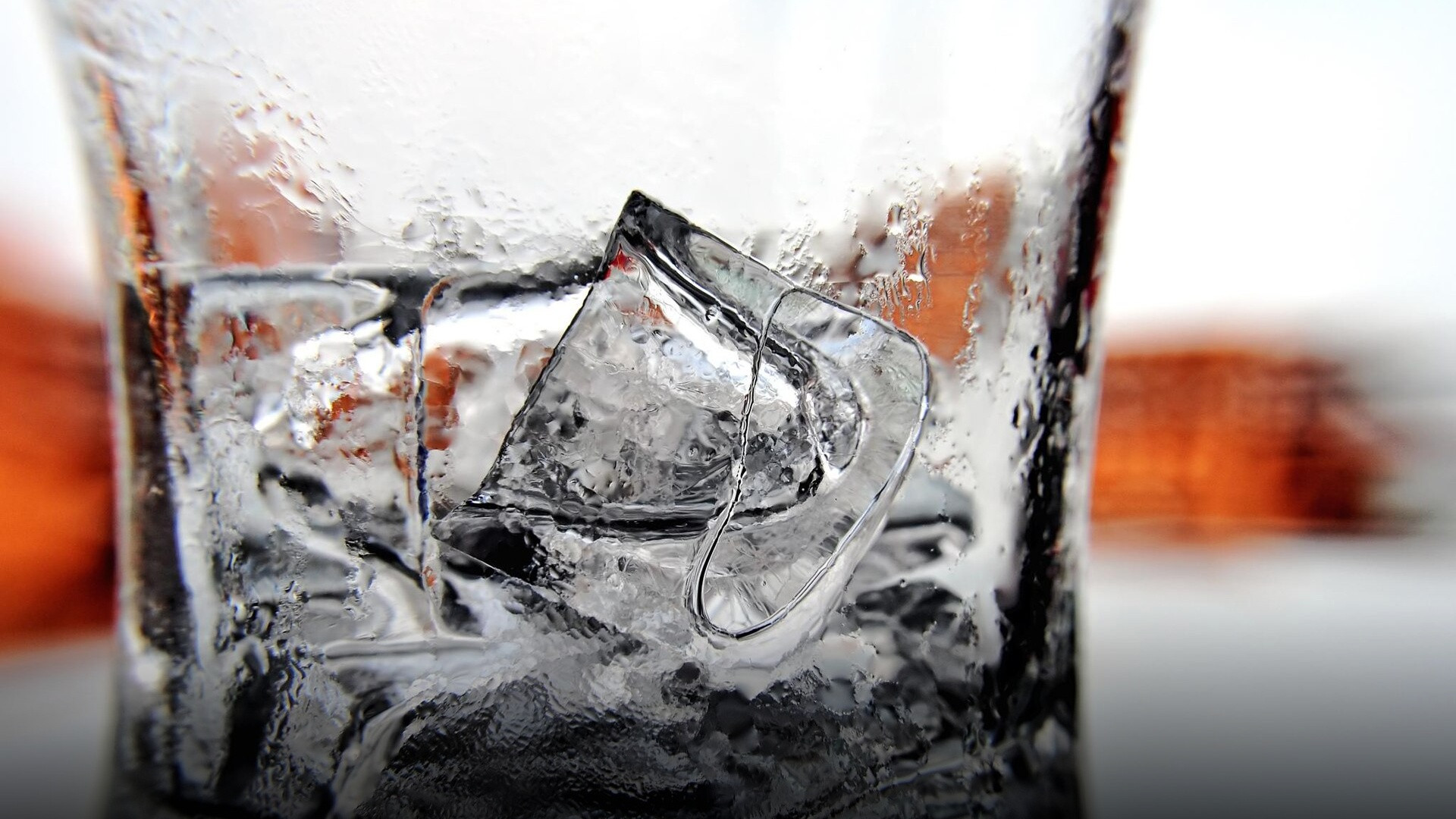 A clear beverage glass packed to the brim with glistening ice cubes.