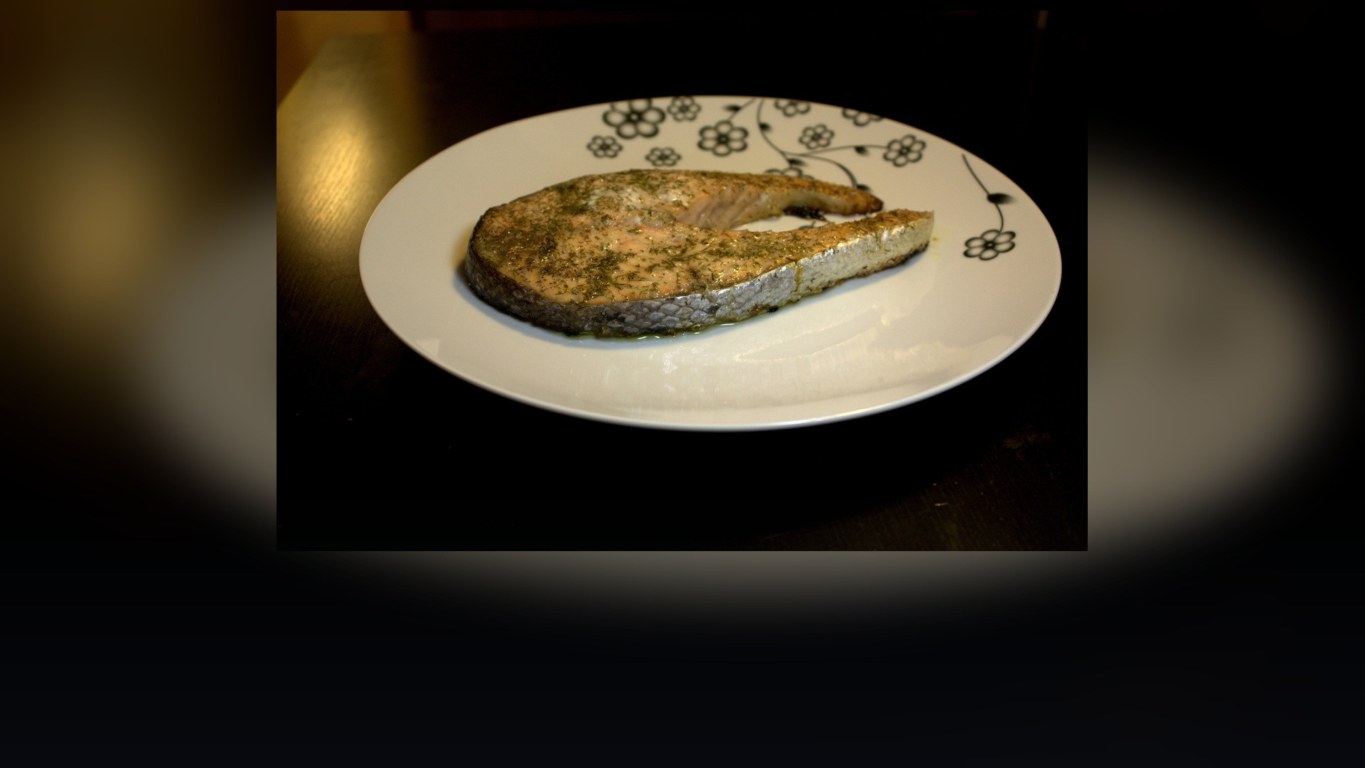 Perfectly cooked tender wild salmon steak plated with herbs on a dinner table.