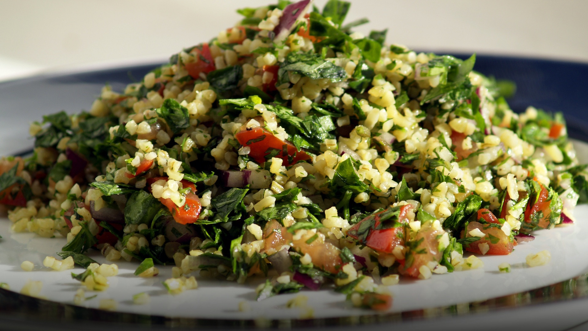 A fresh bowl of Lebanese Tabbouleh salad loaded with finely chopped green parsley, mint, diced red tomatoes, and bulgur.