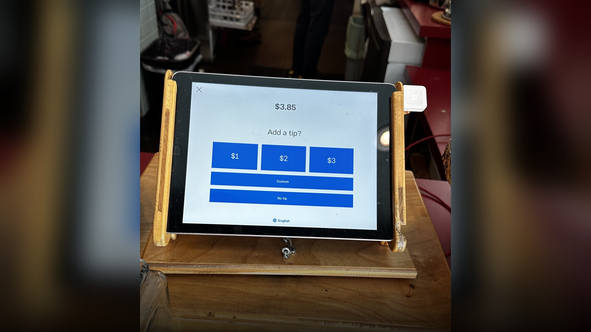 A digital tablet point-of-sale checkout counter prompting the customer to select a tip before completing the transaction.