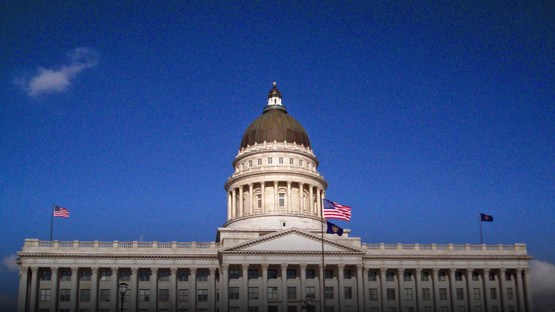 The Utah State Capitol in Salt Lake City framed by snow on the grounds and surrounding hills.