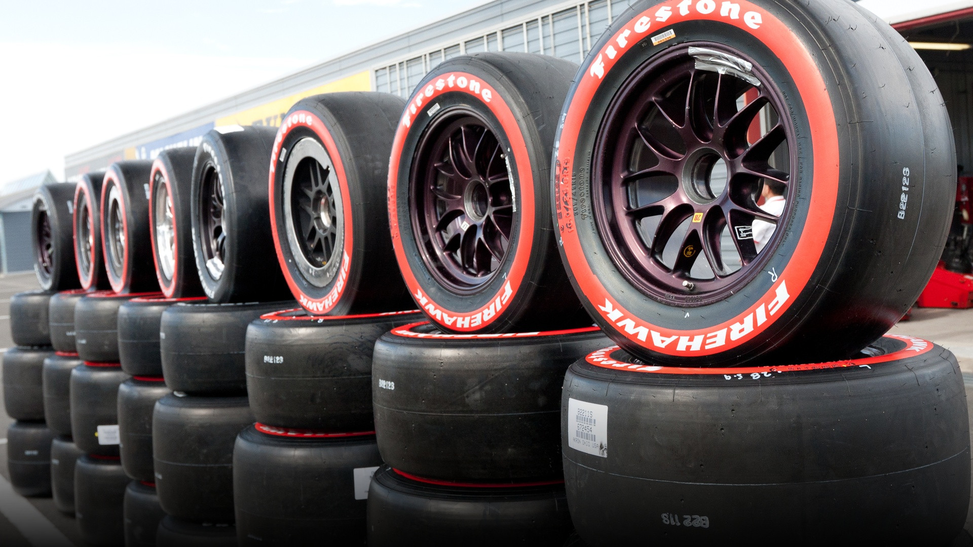 A wide Firestone Firehawk racing slick tire mounted on an IndyCar open-wheel racecar.