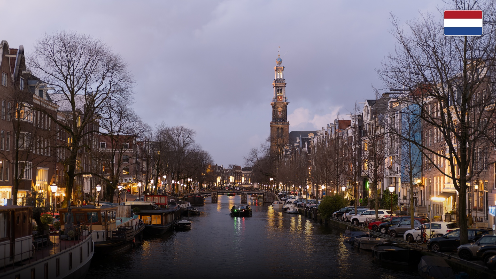 Prinsengracht canal lined with historic brick canal houses, houseboats, and the Westerkerk tower.