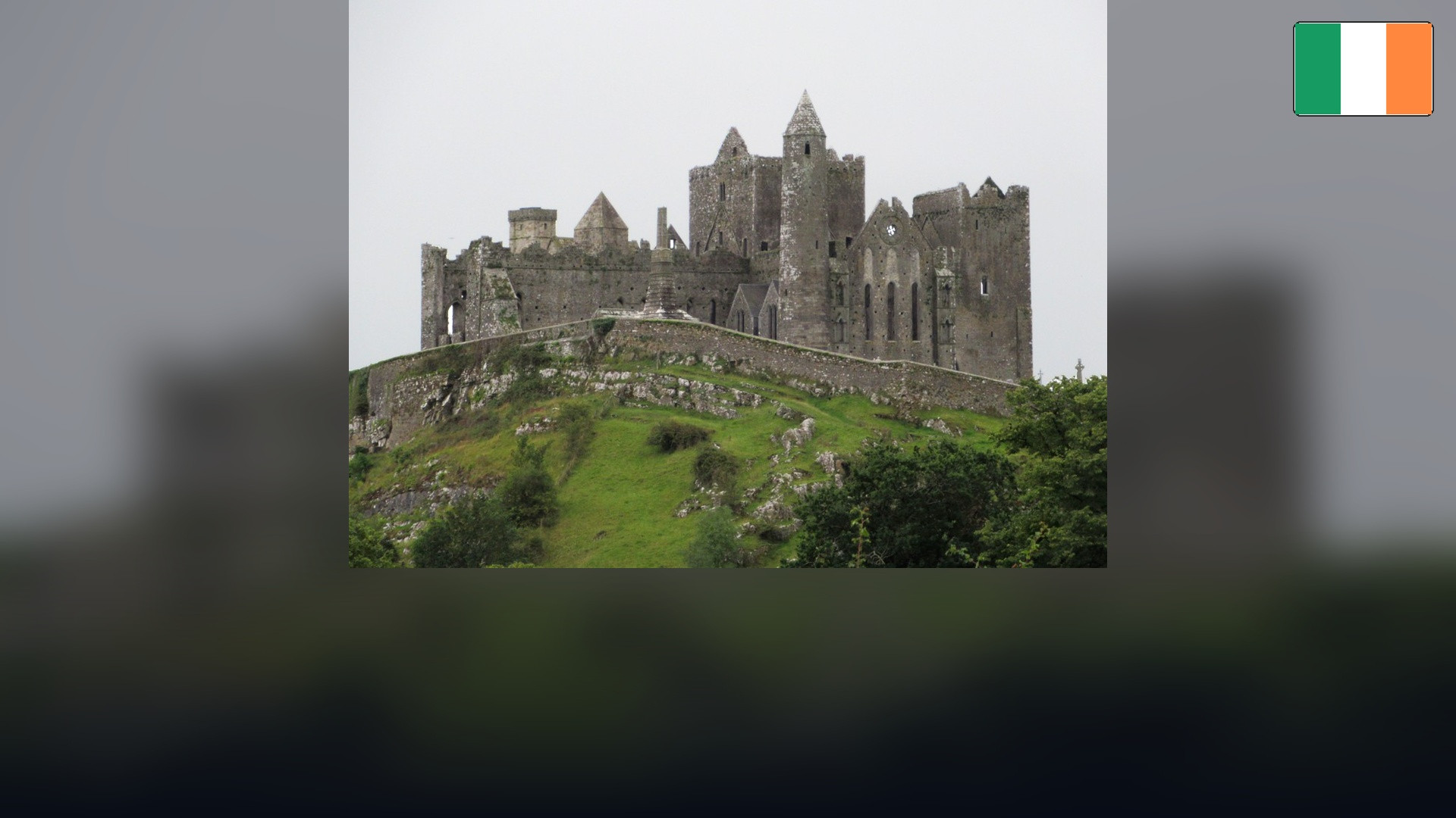 The historic Rock of Cashel with the Irish flag in the top right corner.
