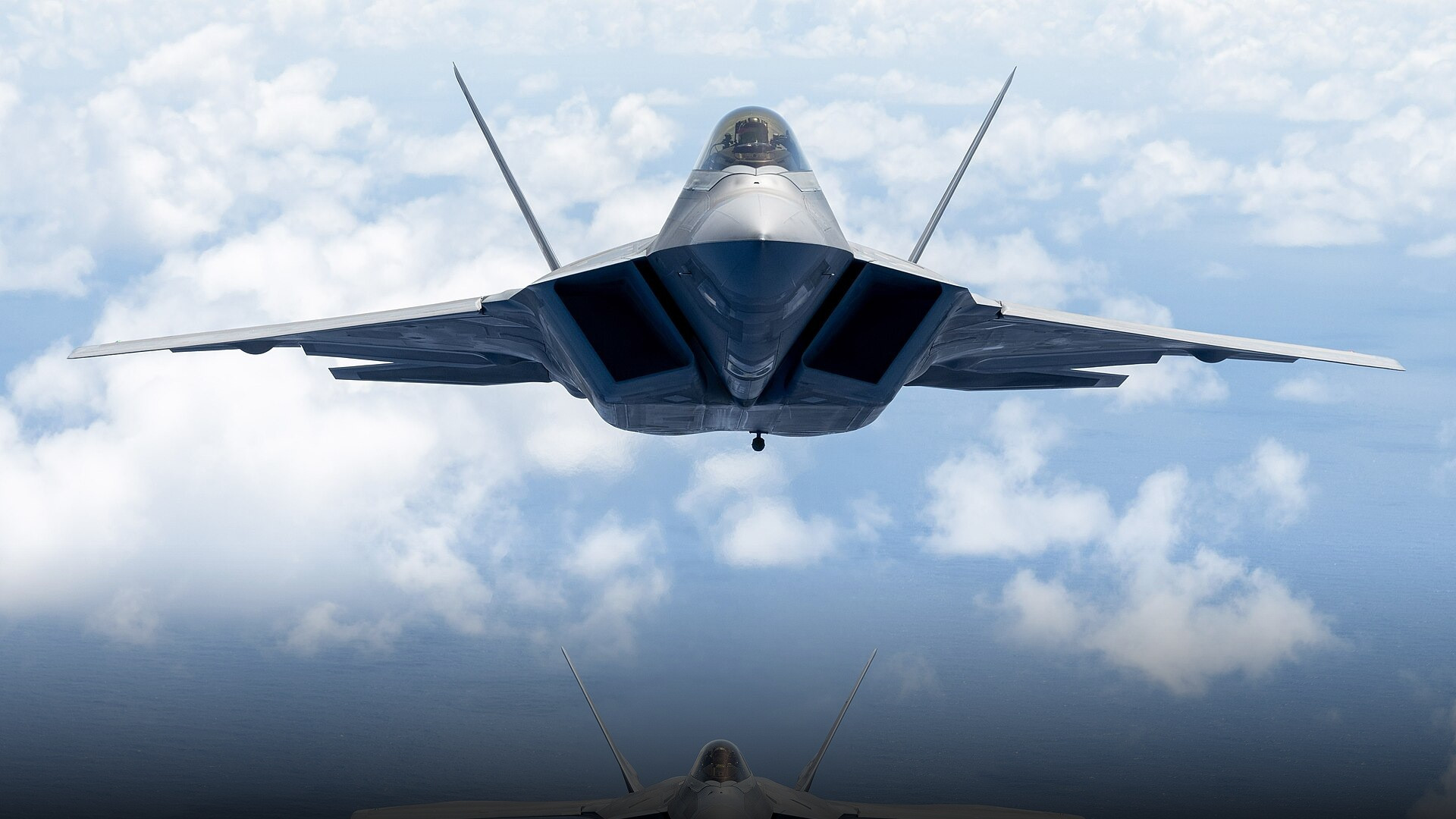 Lockheed Martin F-22 Raptor stealth air superiority fighter soaring above ocean waters.