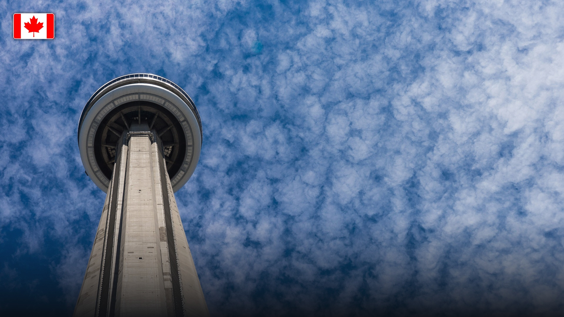 The CN Tower soaring over the modern skyline of Toronto, with the flag of Canada.