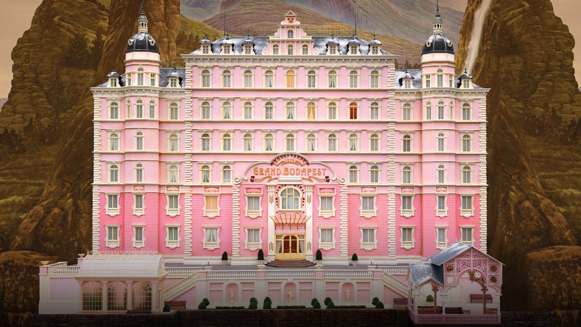 The pastel pink facade of the Grand Budapest Hotel nestled in the alpine mountains of Zubrowka.