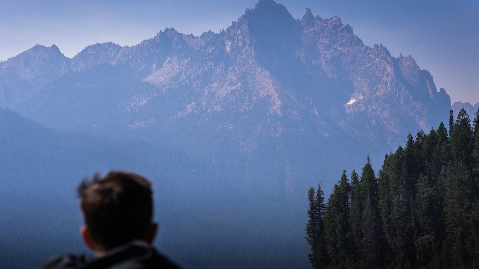 Crystal clear waters of Redfish Lake with small ferry boat and the rugged granite peaks of the Sawtooth Mountains rising dramatically in Idaho.