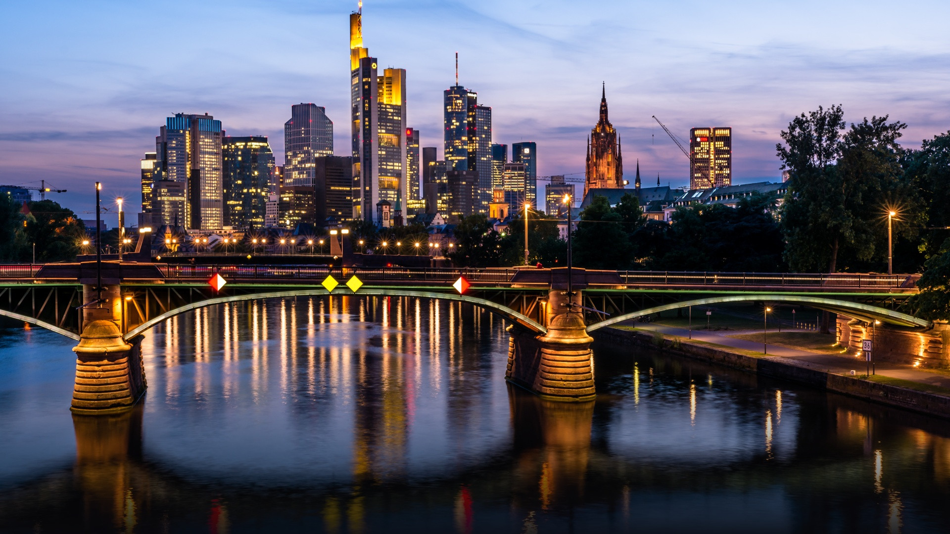 Frankfurt financial district skyline and the Main river at sunset with historic bridges.