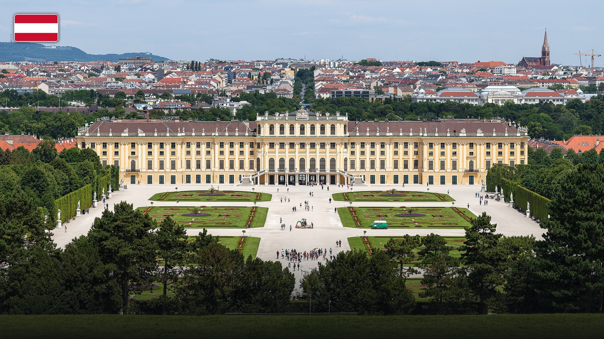 The grand baroque facade and gardens of Schönbrunn Palace in Vienna, with the flag of Austria.