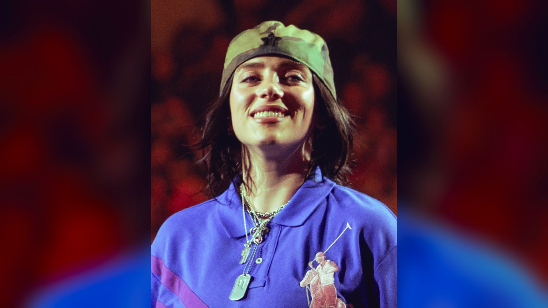 Billie Eilish singing passionately into a microphone at an arena concert.