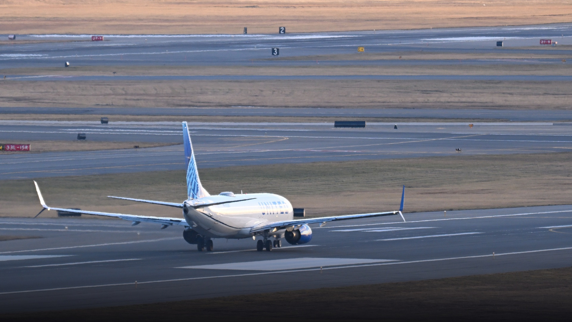 A United Airlines Boeing 737-800 rolling down the runway at Boston Logan International Airport.