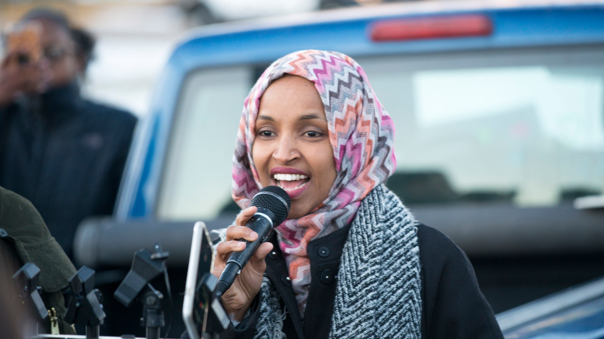 Rep. Ilhan Omar speaking into a microphone at a workers rally in Minnesota