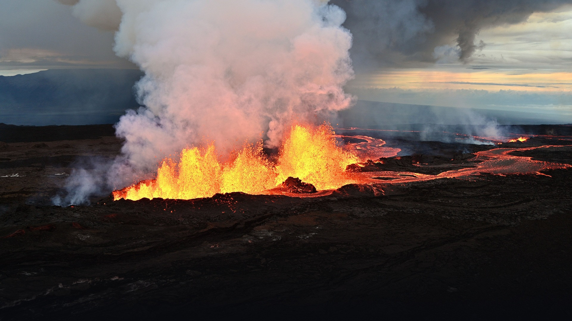 High-altitude morning vista of Mauna Loa erupting fissure with soaring orange-gold lava fountains, glowing lava rivers, and illuminated volcanic steam plume.