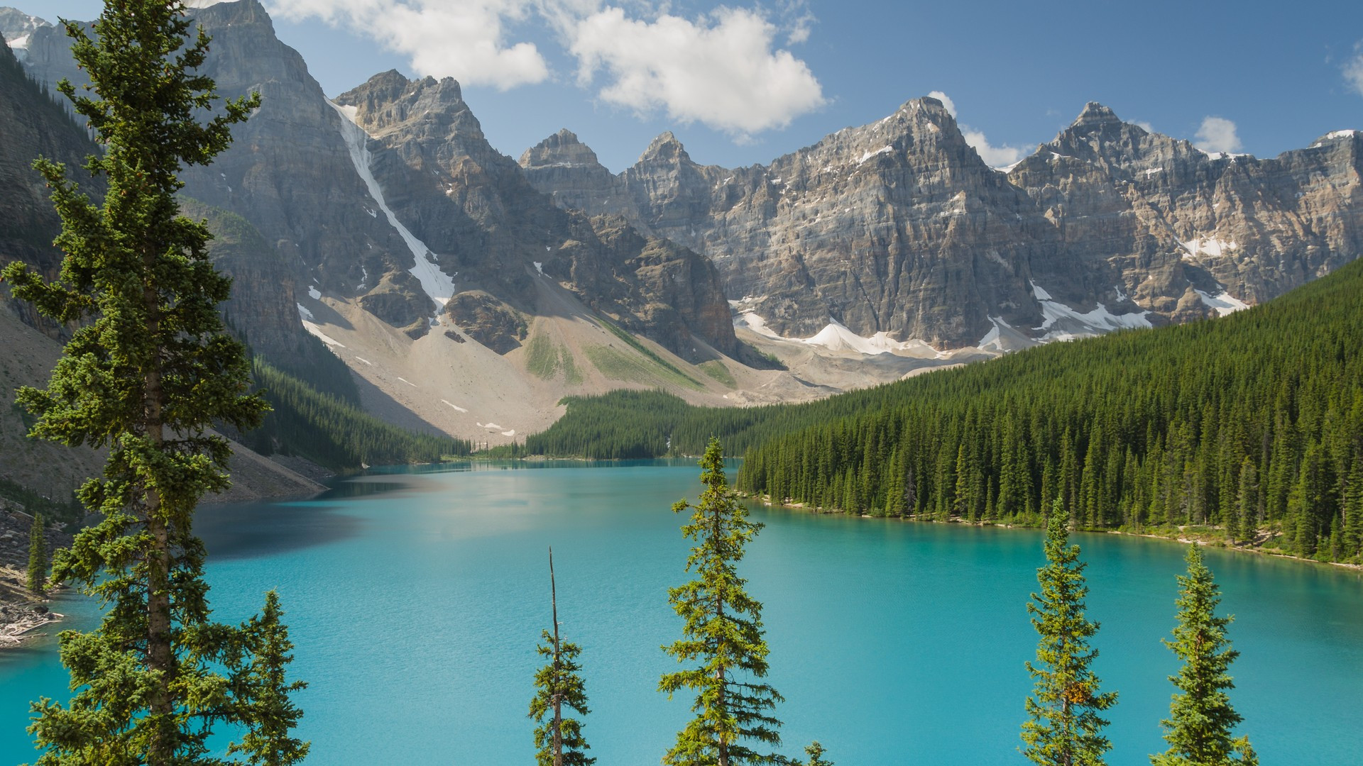 Canoes on the neon turquoise waters of Moraine Lake surrounded by the Valley of the Ten Peaks in Banff.