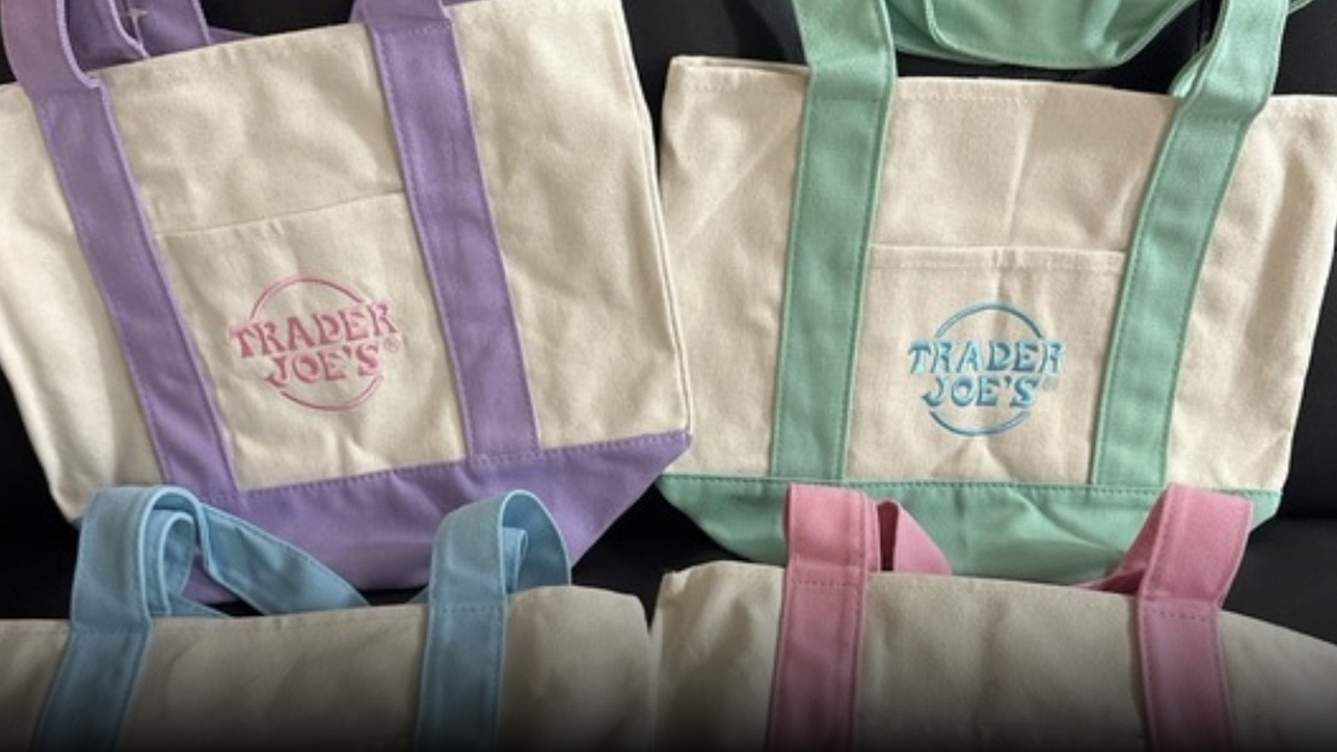 Four colorful pastel Trader Joe's mini canvas tote bags displaying the official embroidered store logo.