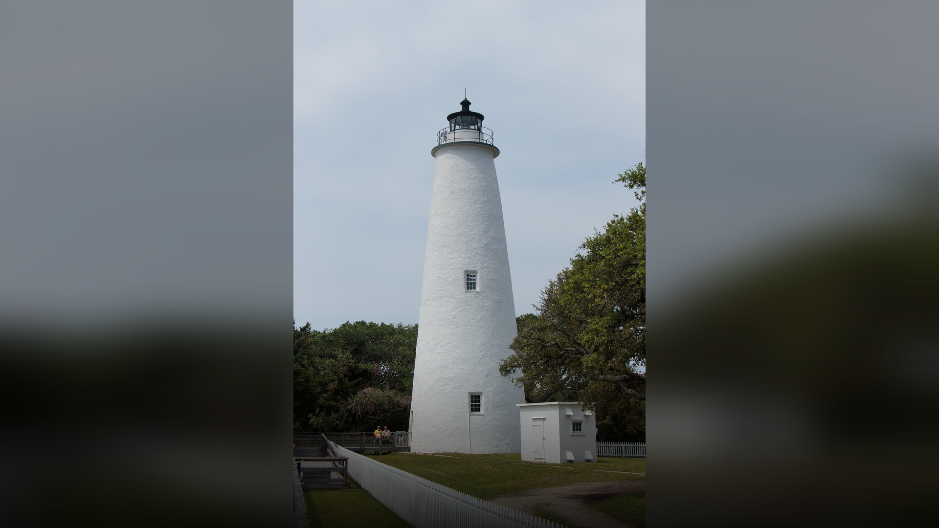 The historic whitewashed Ocracoke Island Lighthouse under a clear coastal blue sky.