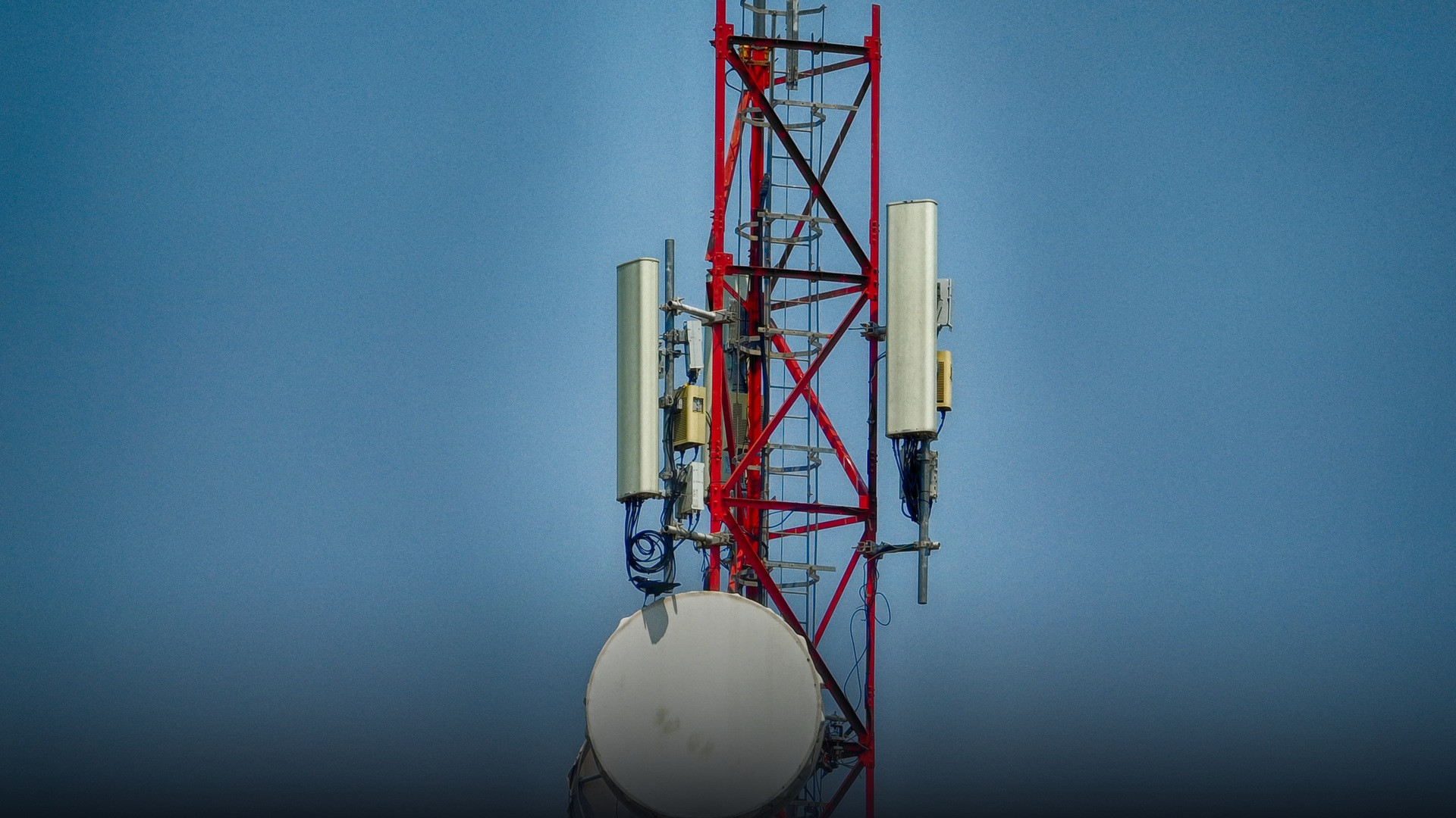 Close up view of cellular communications antenna mast against open sky.