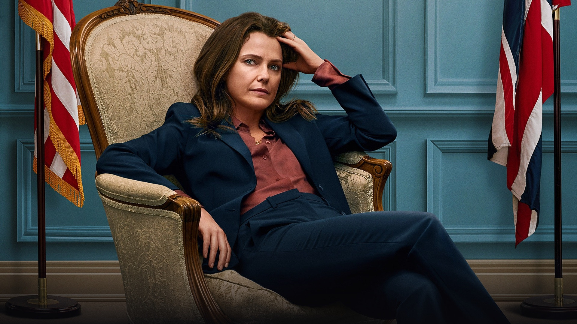Keri Russell as US Ambassador Kate Wyler seated in an ornate ambassadorial armchair flanked by flags.