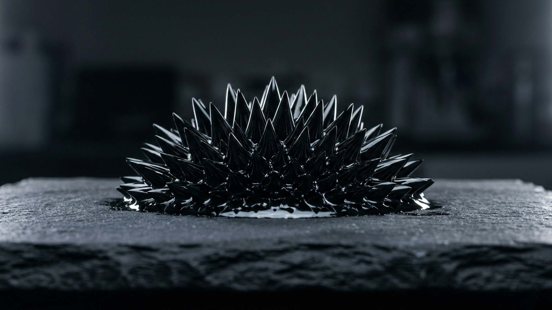 Macro shot of glistening jet-black liquid metal forming hundreds of sharp, needle-like geometric spikes over a cylindrical magnet.