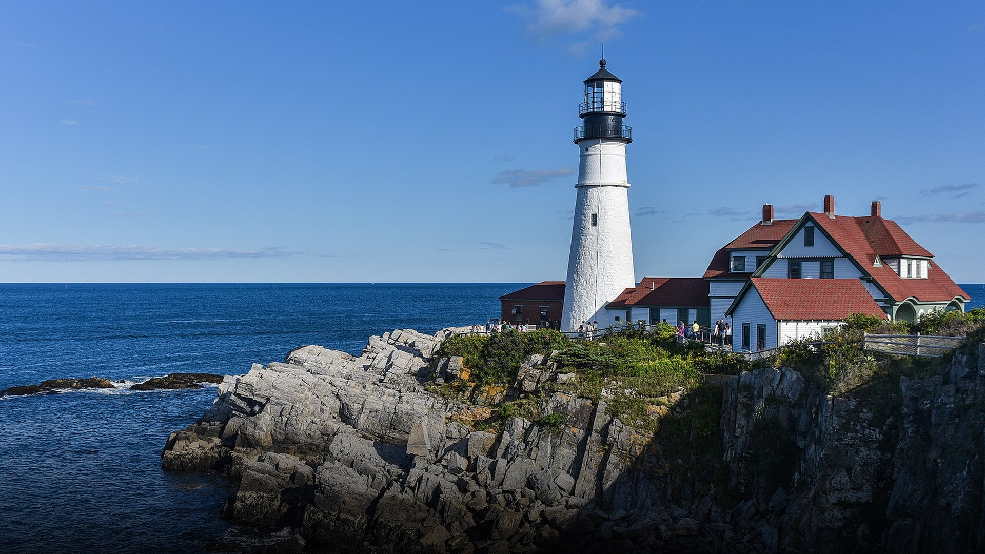 Portland Head Light standing atop rugged, rocky cliffs over the Atlantic ocean in Maine.