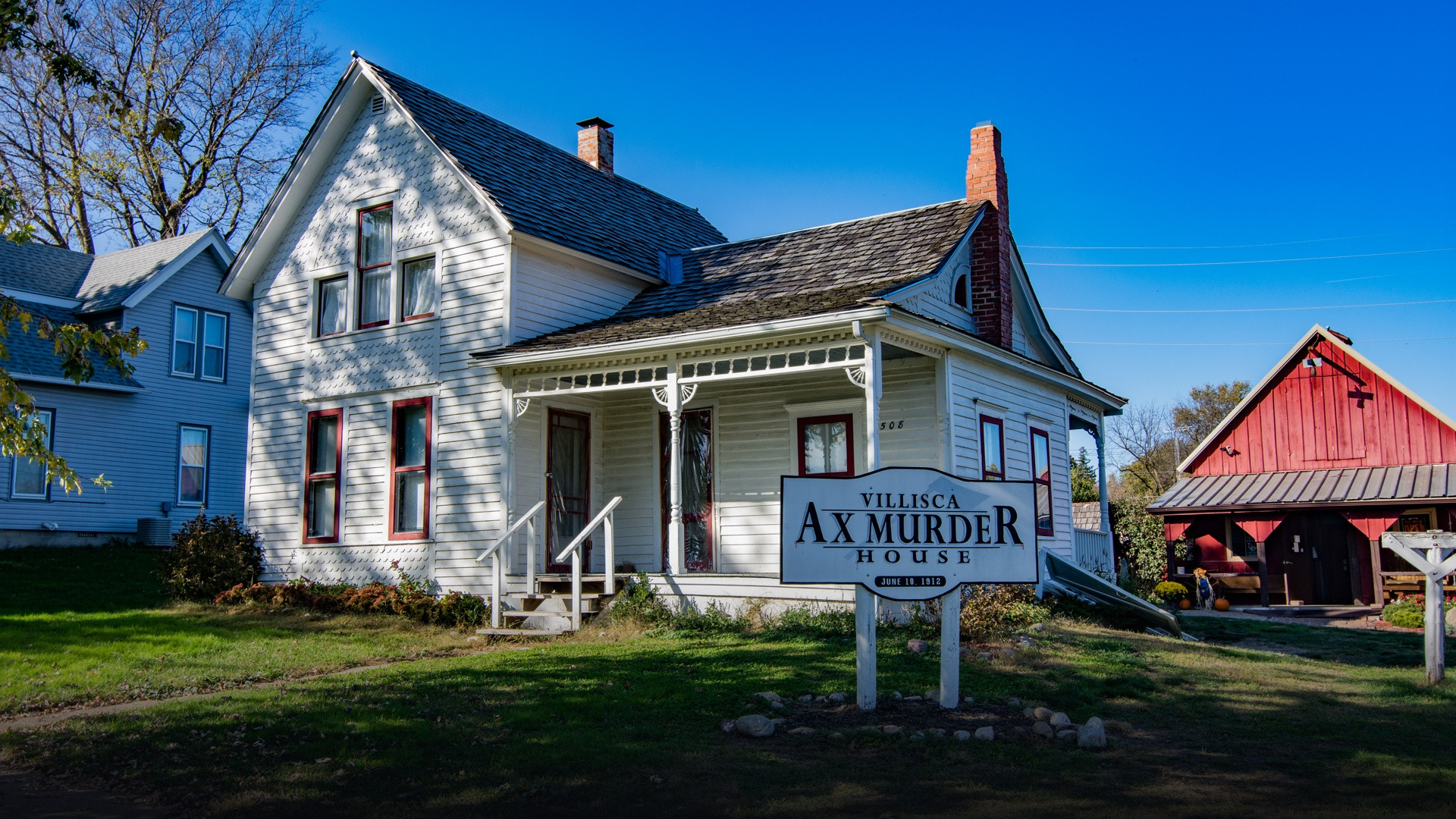 Exterior view of the white two-story Josiah B. Moore residence surrounded by green grass in Villisca, Iowa.