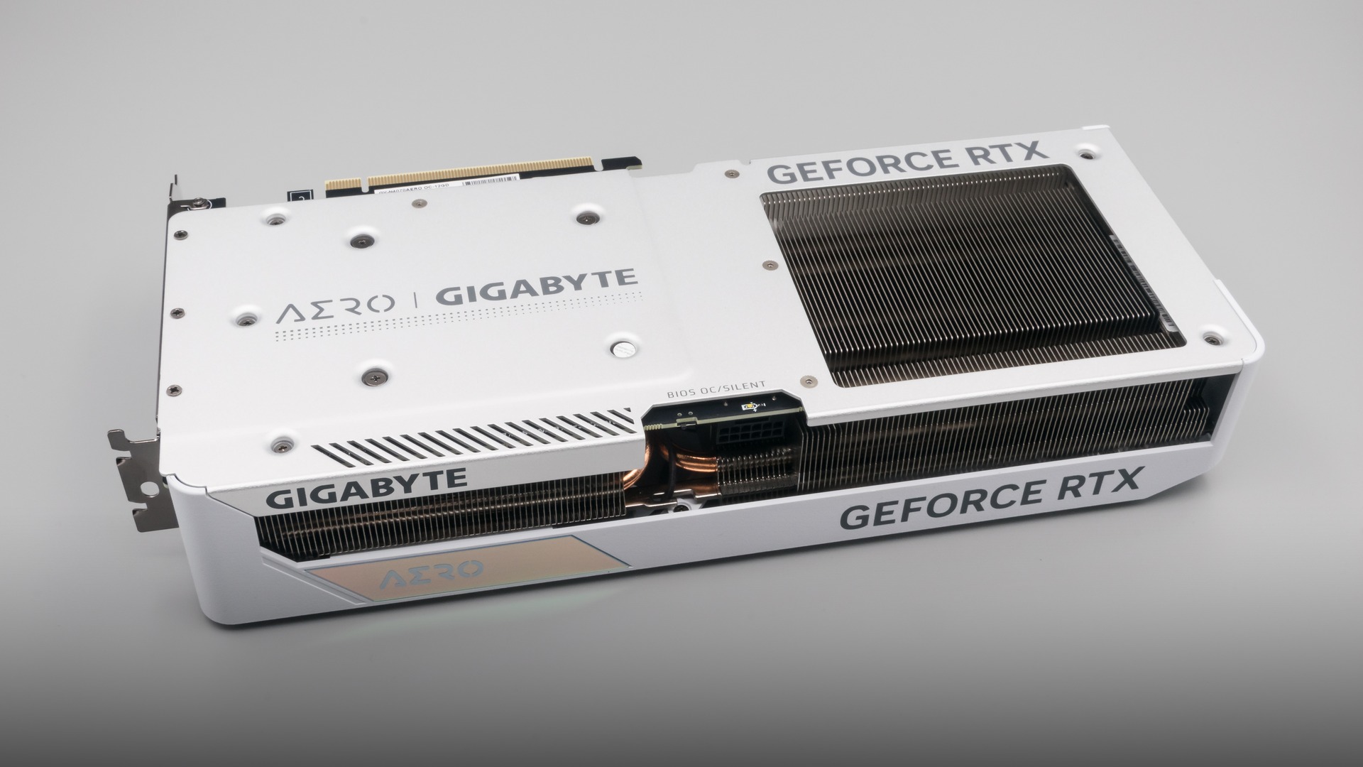 Modern white triple-fan GeForce RTX graphics card with brushed metal cooling shroud resting on a neutral background.