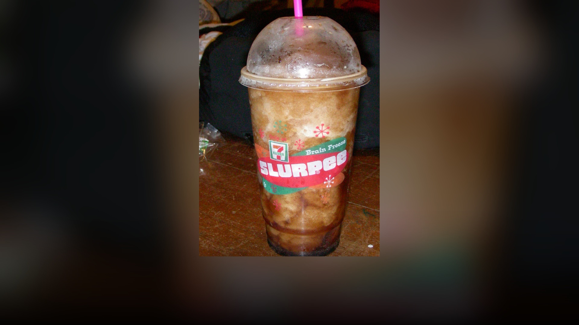 An icy frozen 7-Eleven Slurpee beverage in a branded cup with a pink straw.