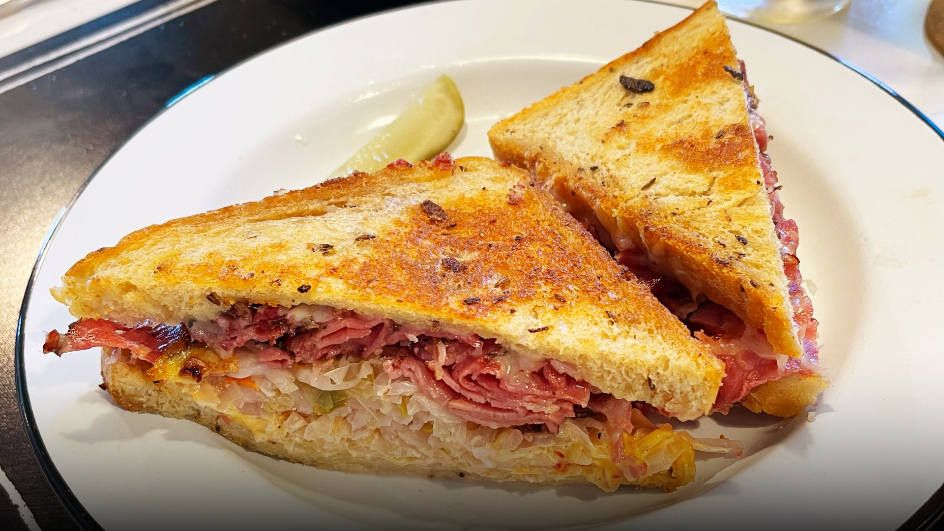 A freshly toasted Reuben sandwich piled with corned beef, melted Swiss cheese, and sauerkraut on rye.