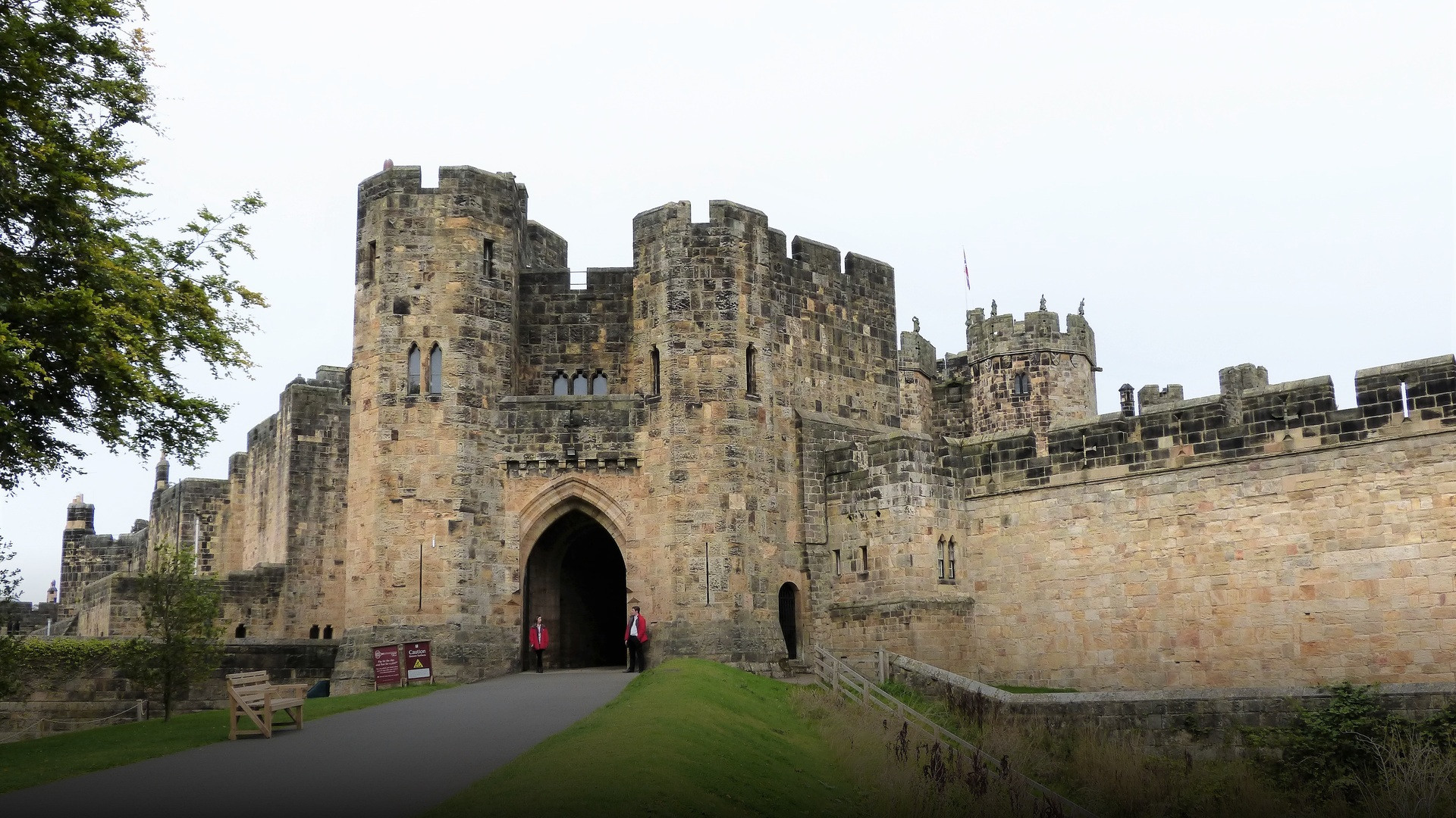 The massive stone gatehouse and defensive walls of Alnwick Castle in Northumberland under clear skies.