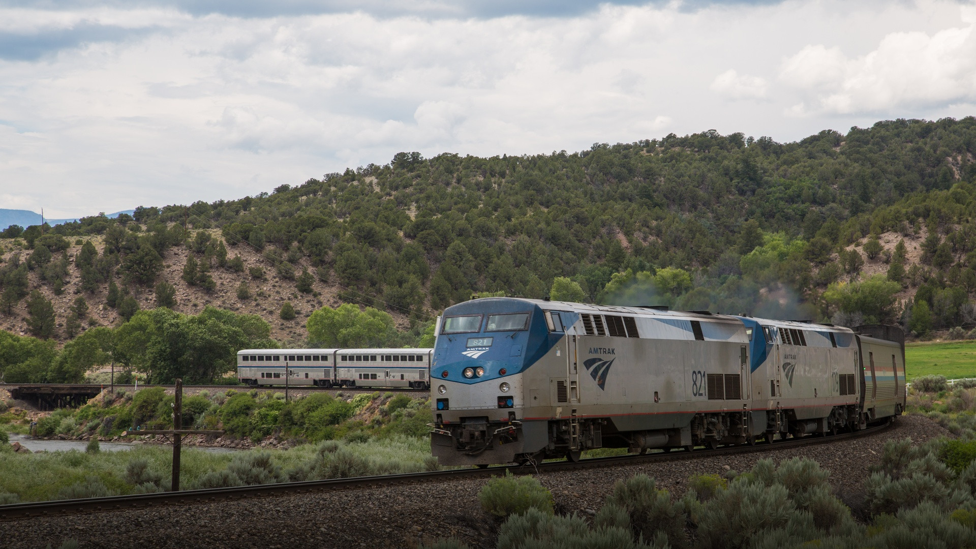 Amtrak California Zephyr locomotive and passenger coaches speeding along the Colorado River canyon flanked by steep mountain slopes