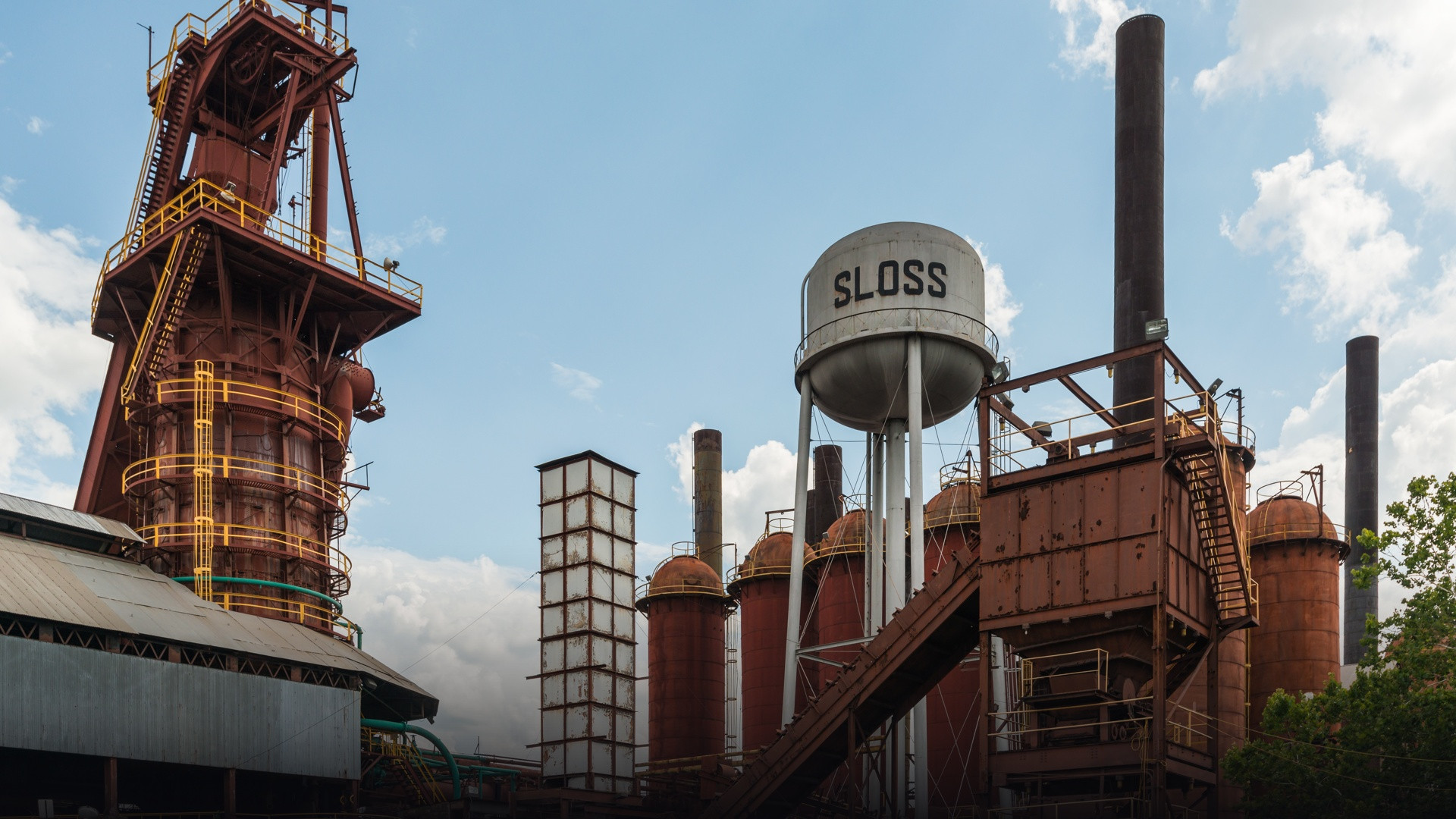 Towering iron blast pipes, rusted metal structures, and industrial smokestacks of Sloss Furnaces in Birmingham, Alabama.