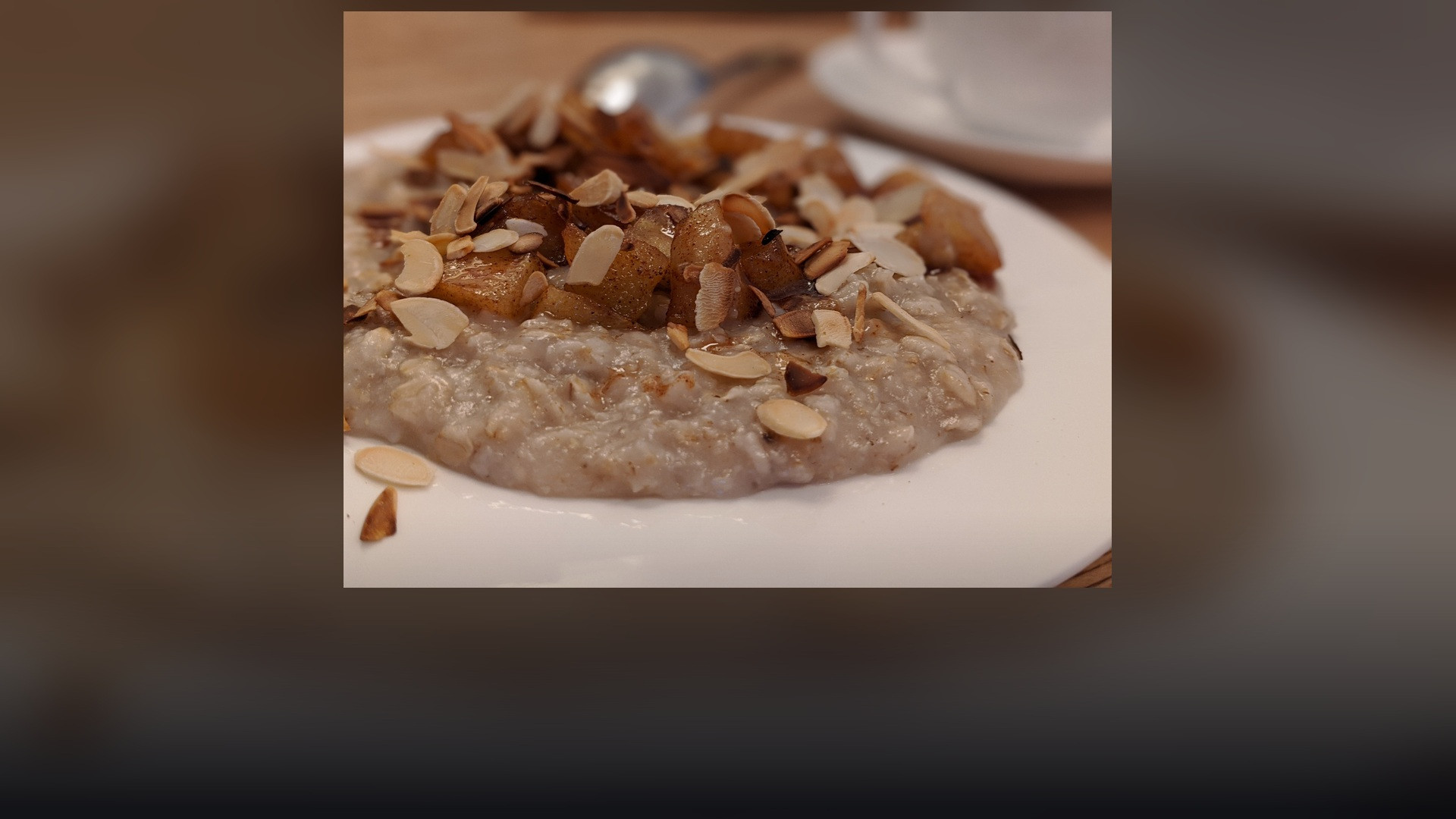 Warm cooked rolled oats oatmeal topped with apple slices and cinnamon.