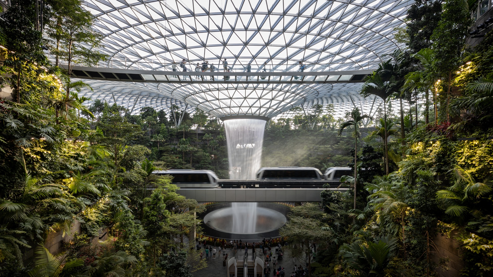 The iconic Jewel Changi Rain Vortex indoor waterfall surrounded by lush green terraced forest.