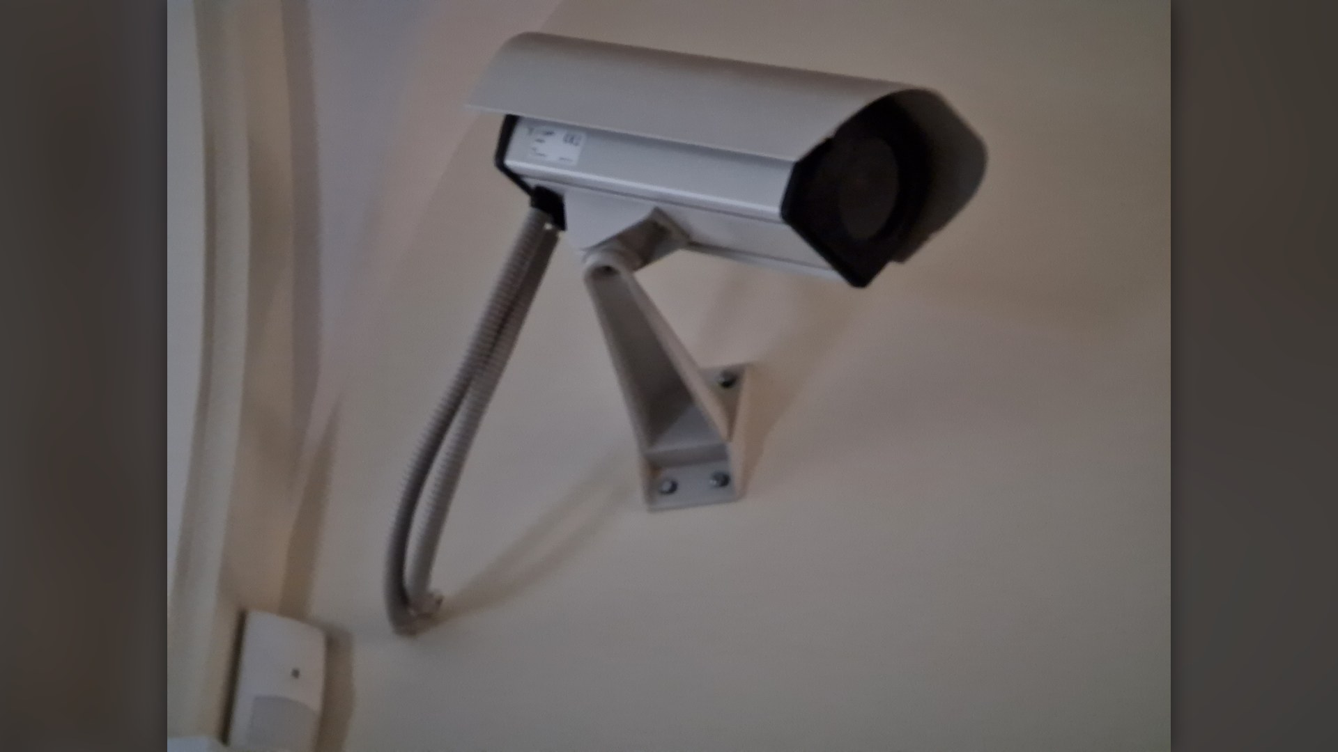 Mounted electronic CCTV security surveillance camera on building exterior.
