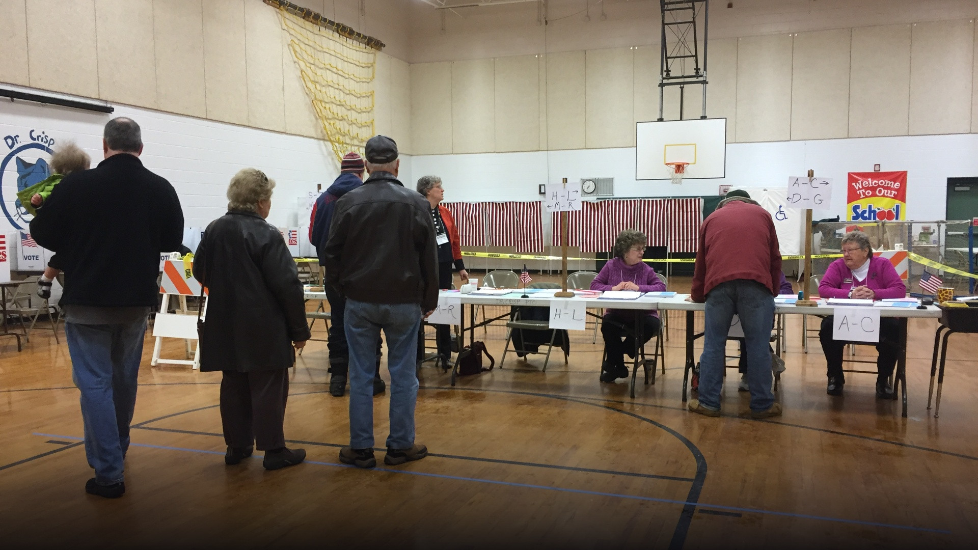 Voters filling out paper ballots at private voting booths inside an active New Hampshire polling precinct.