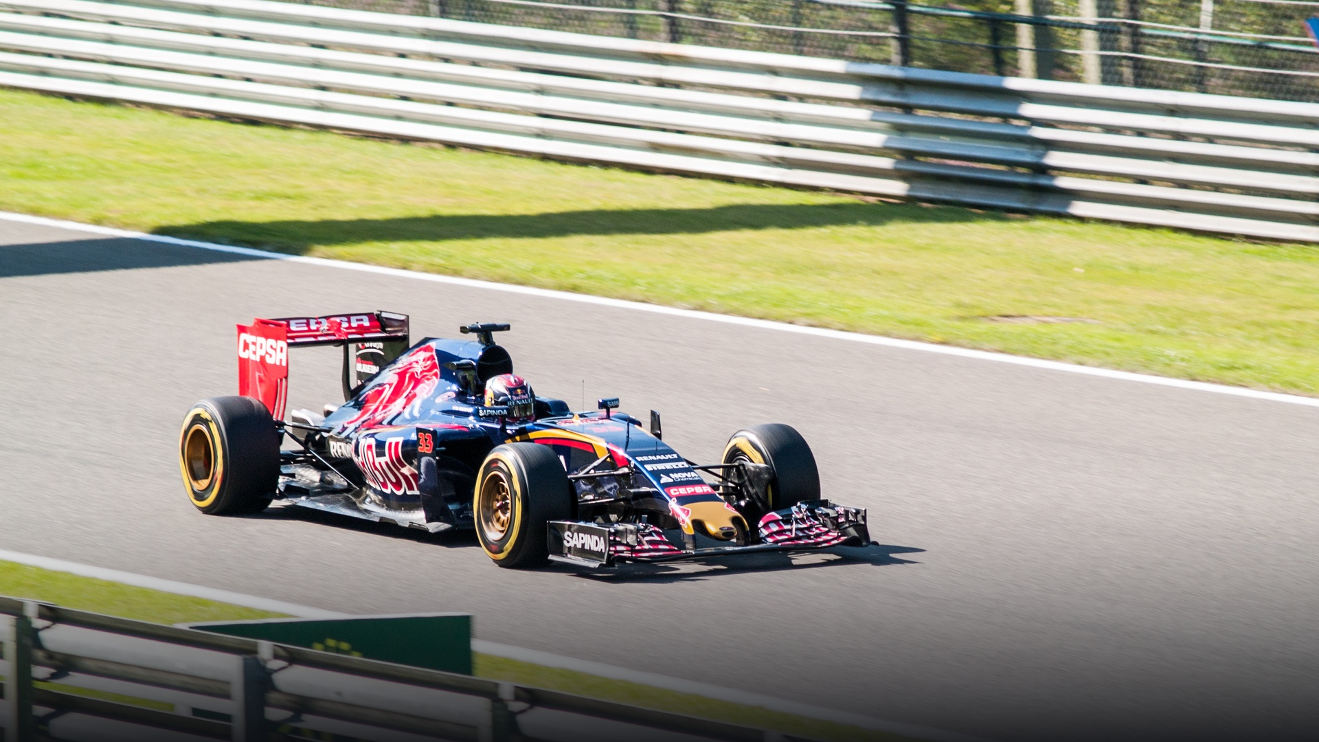 Max Verstappen piloting the blue and gold Scuderia Toro Rosso STR10 race car through a high-speed corner.